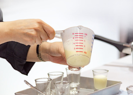 Measuring out milk in a measuring jug for cooking or testの写真素材