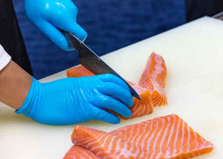 chef slicing raw fresh salmon, Chef preparing a fresh salmon on a cutting boardの写真素材