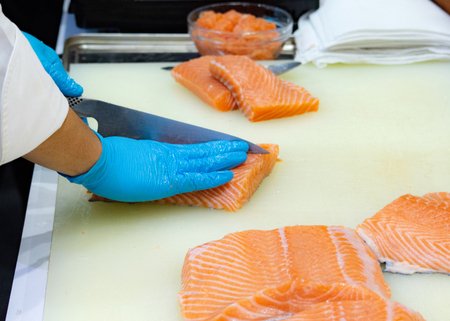 chef slicing raw fresh salmon, Chef preparing a fresh salmon on a cutting boardの写真素材