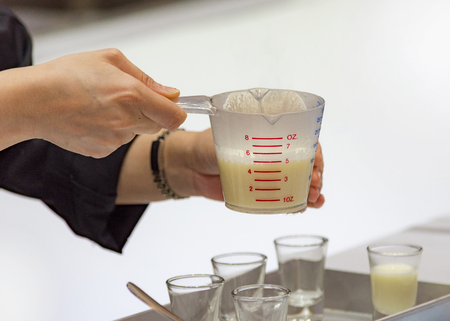 Measuring out milk in a measuring jug for cooking or testの写真素材