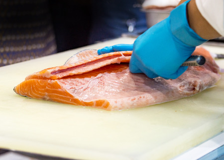 chef slicing raw fresh salmon, Chef preparing a fresh salmon on a cutting boardの写真素材