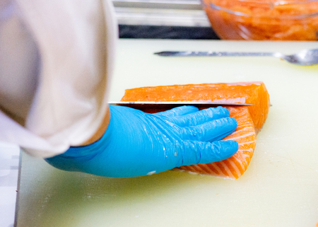 chef slicing raw fresh salmon, Chef preparing a fresh salmon on a cutting boardの写真素材