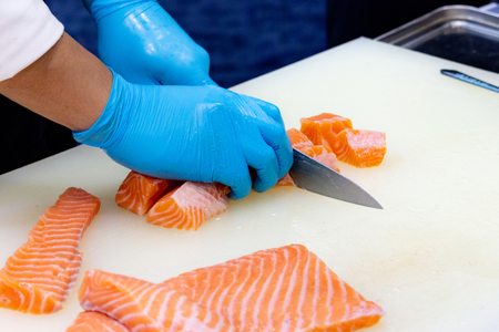 chef slicing raw fresh salmon, Chef preparing a fresh salmon on a cutting boardの写真素材