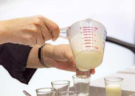 Measuring out milk in a measuring jug for cooking or testの写真素材