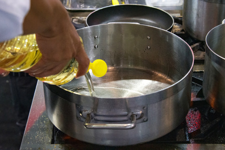 Chef pouring oil in frying pan, Chef cooking food in the kitchenの写真素材