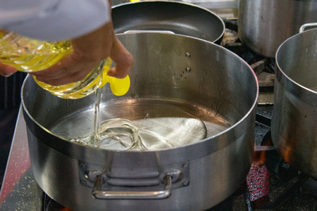 Chef pouring oil in frying pan, Chef cooking food in the kitchenの写真素材