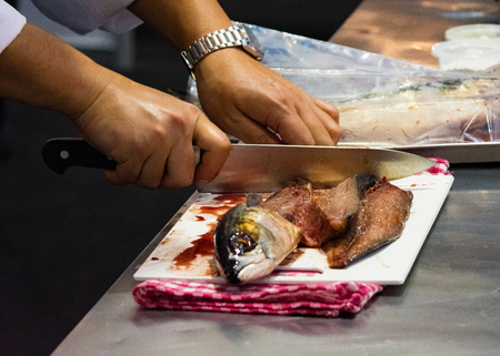 Chef cutting fish, Chef slices fish fresh on Board in the kitchenの写真素材