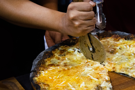Chef cutting freshly baked pizza, prepared pizza homemadeの写真素材