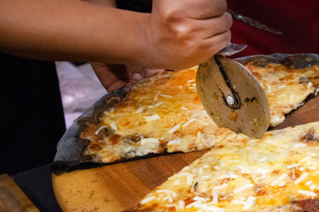 Chef cutting freshly baked pizza, prepared pizza homemadeの写真素材