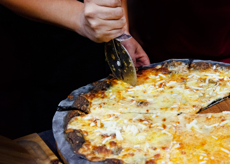 Chef cutting freshly baked pizza, prepared pizza homemadeの写真素材