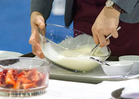 Hands preparing cream, chef whisking cream in kitchenの写真素材