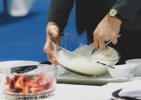 Hands preparing cream, chef whisking cream in kitchenの写真素材