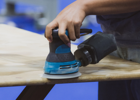 Carpenter using sander for wood table surfaceの写真素材