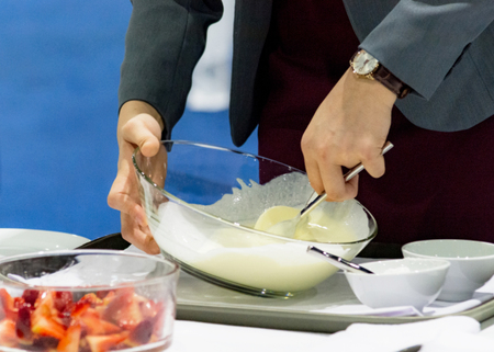 Hands preparing cream, chef whisking cream in kitchenの写真素材