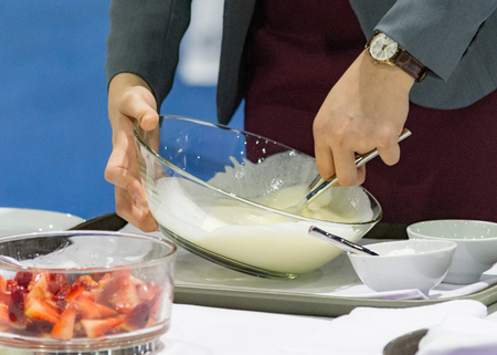 Hands preparing cream, chef whisking cream in kitchenの写真素材