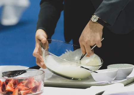 Hands preparing cream, chef whisking cream in kitchenの写真素材