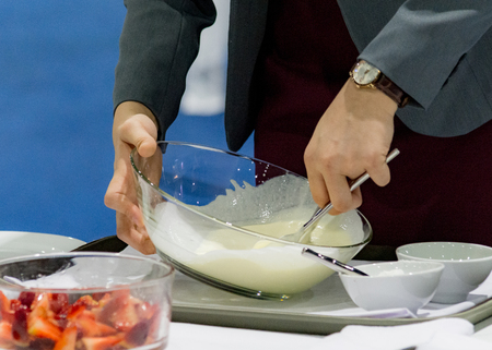Hands preparing cream, chef whisking cream in kitchenの写真素材