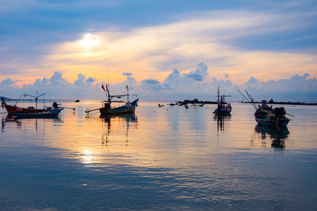 Fishing boat in the sea, sunset and silhouettes of wooden boats の写真素材