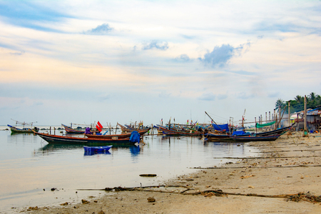 Fishing boat in the sea, sunset and silhouettes of wooden boatsの写真素材