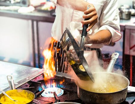 Chef cooking with flame in a frying pan on a kitchen stove