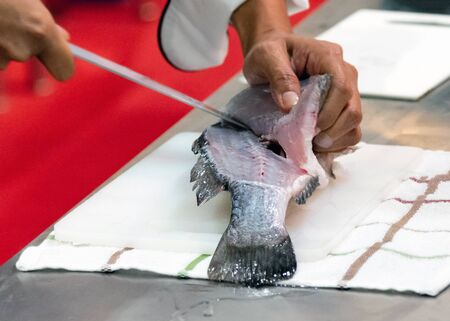 Chef cutting fish, Chef slices fish fresh on Board in the kitchenの写真素材