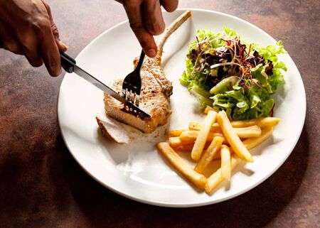 knife cutting grilled pork chops steak Close up, Pork chop steak with salad and french fries