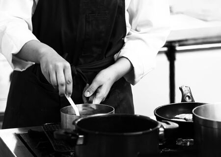 chef cooking in a kitchen, chef at work, black & white backgroundの写真素材