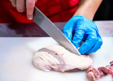 Chef cutting chicken meat on kitchenの写真素材