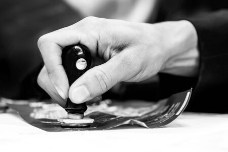 Close up Hands Stamping on ticket at Desk black and white photographyの写真素材