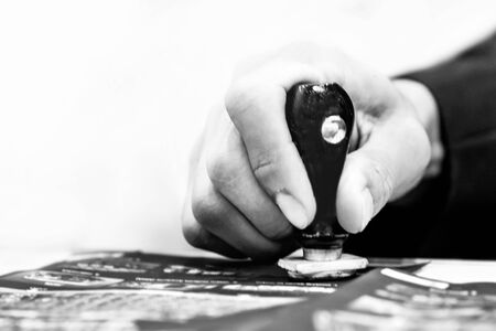 Close up Hands Stamping on ticket at Desk black and white photographyの写真素材