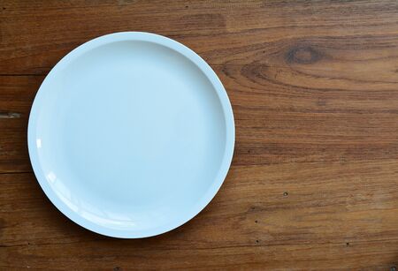 Empty white plate on wooden table