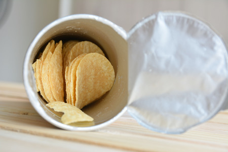 Slice potato chips in can on wood table