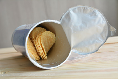 Slice potato chips in can on wood tableの写真素材