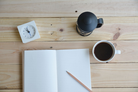 Coffee time concept. A cup of coffee with notebook with Watch on wooden backgroundの写真素材