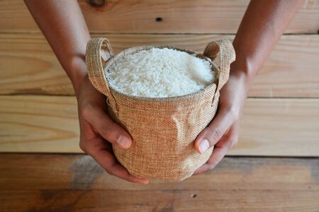 Jasmine rice in sack on wooden tableの写真素材