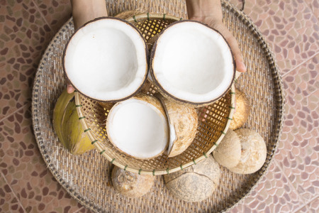 Open coconut with coconut peel and hand on bamboo matの写真素材