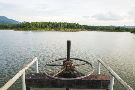 Water gate valve and lake with skyの写真素材