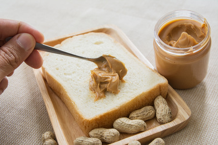 Peanut butter sandwich or toast on wooden plate with peanut shellの写真素材