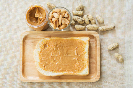 Peanut butter sandwich or toast on wooden plate with peanut shell