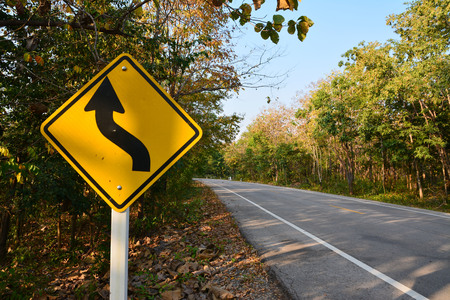 Asphalt road with curve traffic sign in forest