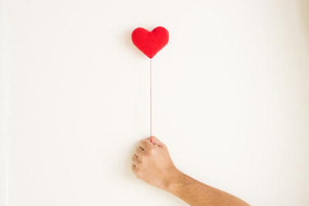 Love background, hand holding red heart  knitting shape on white backgroundの写真素材