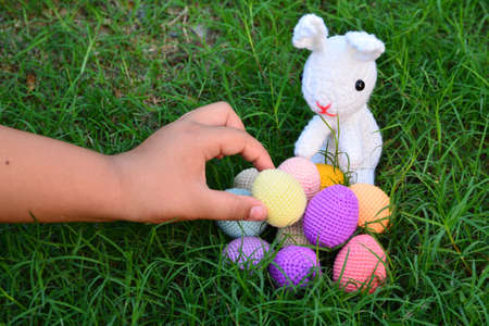 Knitting Easter eggs with rabbit on the grass