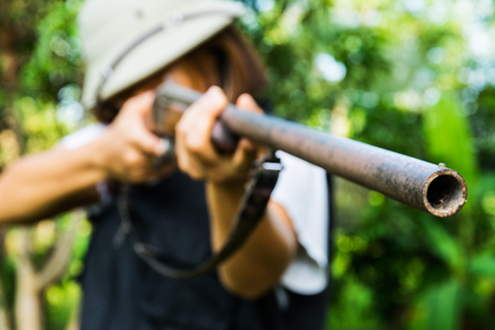 Hunter Women are aiming guns at green forest