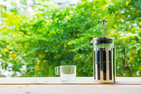 Hands holding french press coffee pot and cup on green backgroundの写真素材
