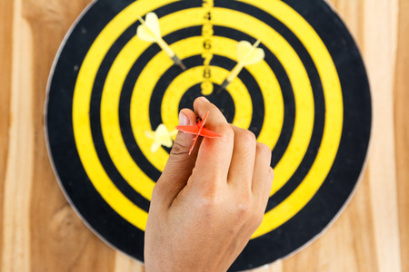 Red dart arrow on center of dartboard isolated on white backgroundの写真素材