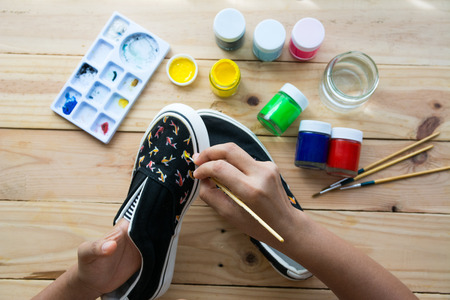 Hand made painted canvas shoes with acrylic paint and paintbrushの写真素材