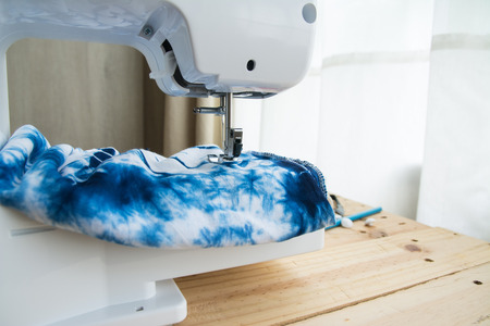 Sewing machine with sewing supplies and fabric on wood table