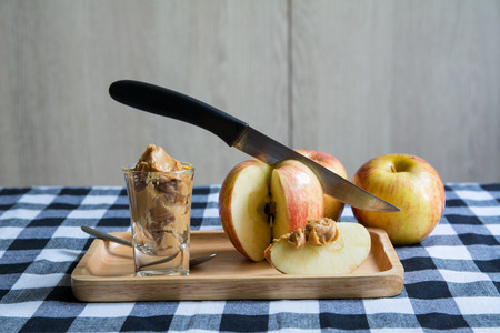 Apples with peanut butter on wooden table