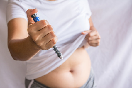Diabetes concept insulin syringe injection shot into abdomenの写真素材