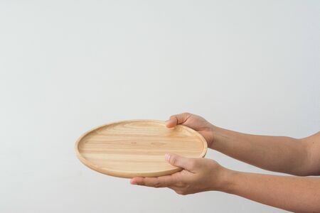Hand holding a wooden dish on white backgroundの写真素材